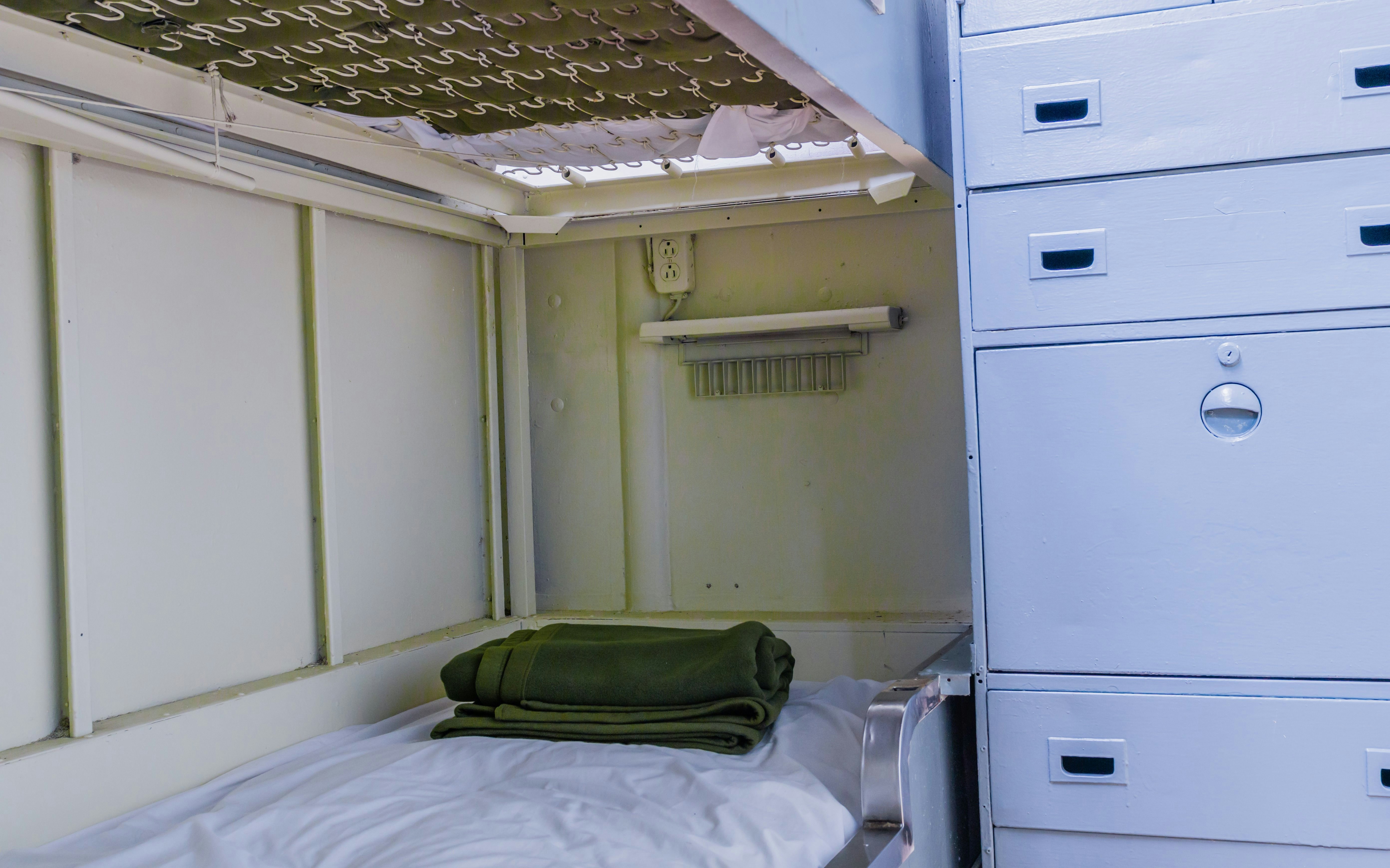 Bunk bed with folded blanket in ship's crew quarters.