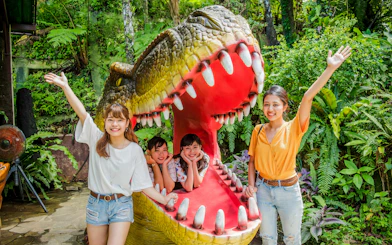 Visitors posing with dinosaur sculpture at Okashigoten Nago Dino Park Yanbaru Subtropical Forest.