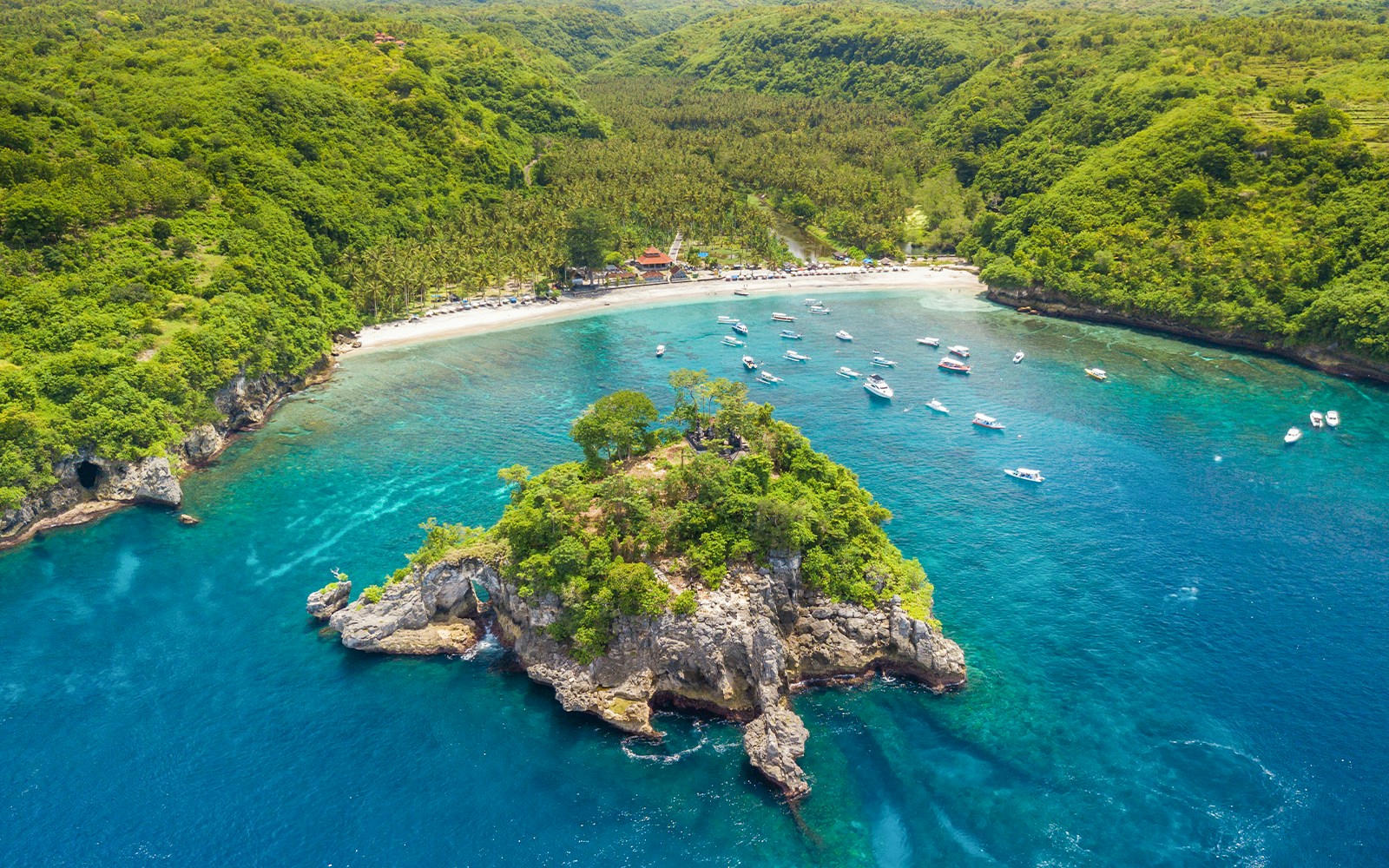 Tourists snorkeling in Crystal Bay, Nusa Penida, with vibrant coral reefs and clear blue waters.