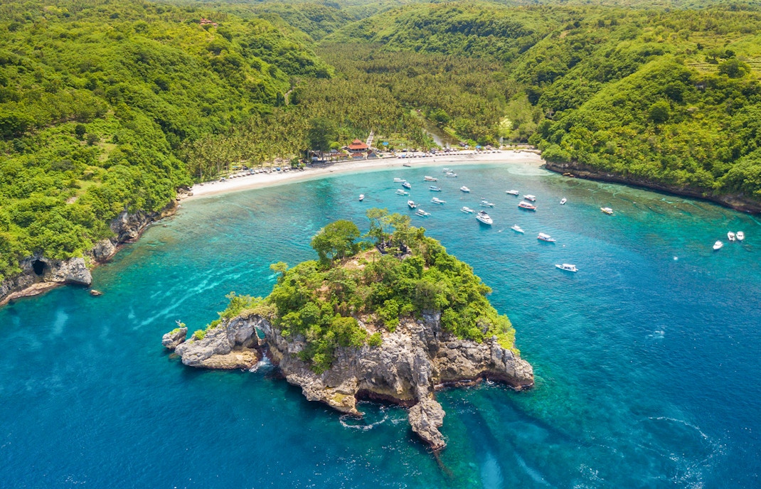 Tourists enjoying the coastline and boats at West Nusa Penida Island, Indonesia.