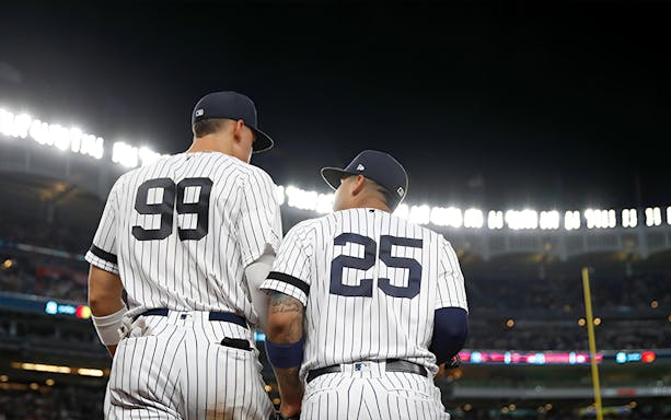 Baseball players in New York Yankees uniforms at Yankee Stadium during a night game.