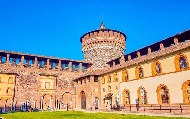 Sforza Castle battlements and tower in Milan, Italy, under a clear blue sky.