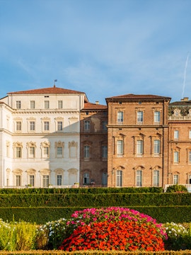 Baroque palace facade with colorful garden in Venaria Reale, Italy.
