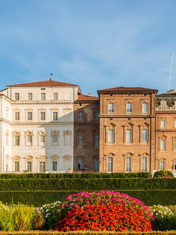 Baroque palace facade with colorful garden in Venaria Reale, Italy.