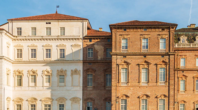 Baroque palace facade with colorful garden in Venaria Reale, Italy.