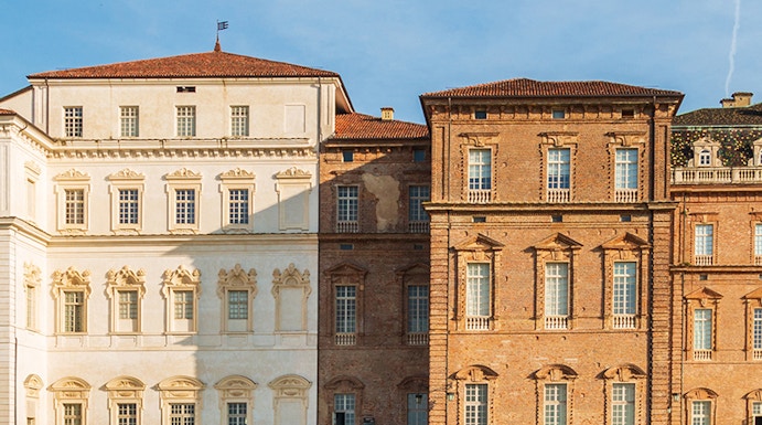 Baroque palace facade with colorful garden in Venaria Reale, Italy.