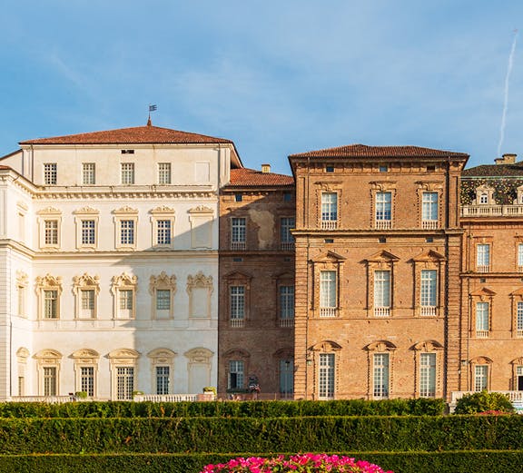 Baroque palace facade with colorful garden in Venaria Reale, Italy.