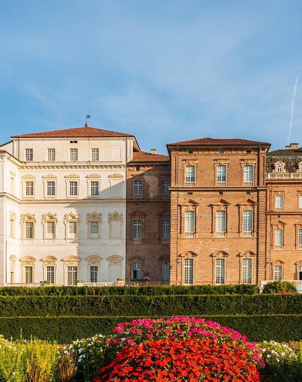Baroque palace facade with colorful garden in Venaria Reale, Italy.
