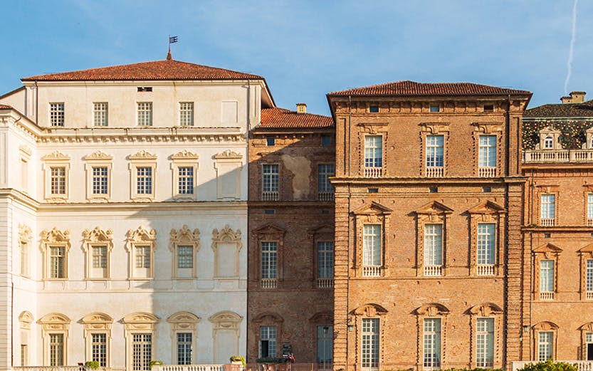 Baroque palace facade with colorful garden in Venaria Reale, Italy.