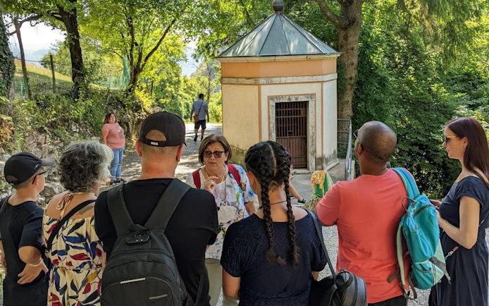 Tour group listening to a guide near a small chapel on the Sirmione, Lazise, and Madonna della Corona Sanctuary tour.