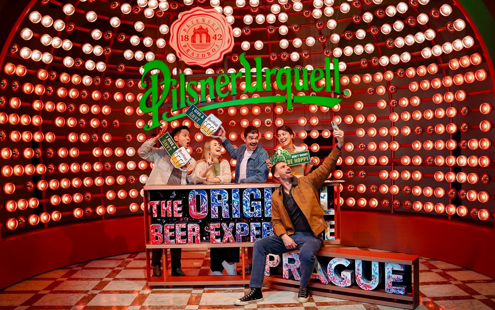 Group enjoying the Pilsner Urquell Experience in Prague with beer-themed props.
