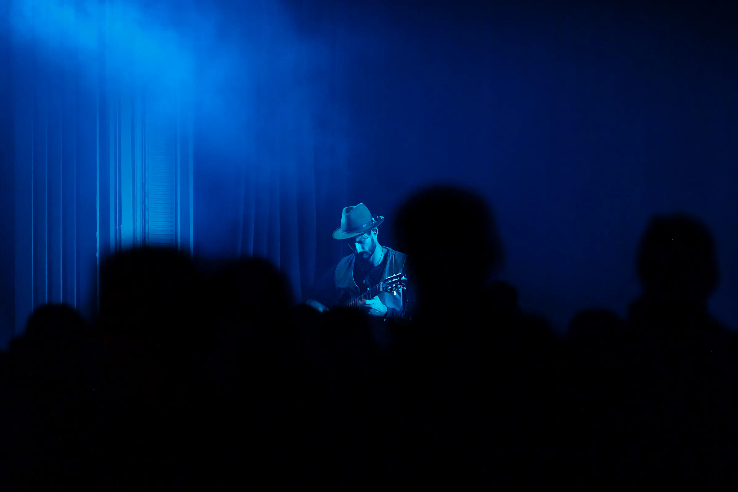 Musician playing guitar on stage during Sacred Sounds event in London.