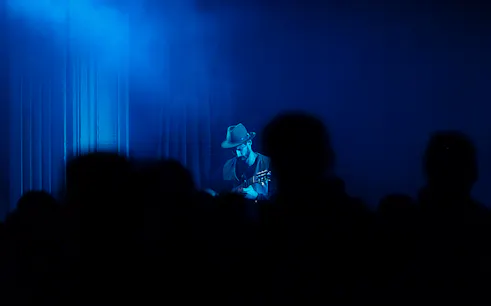 Musician playing guitar on stage during Sacred Sounds event in London.