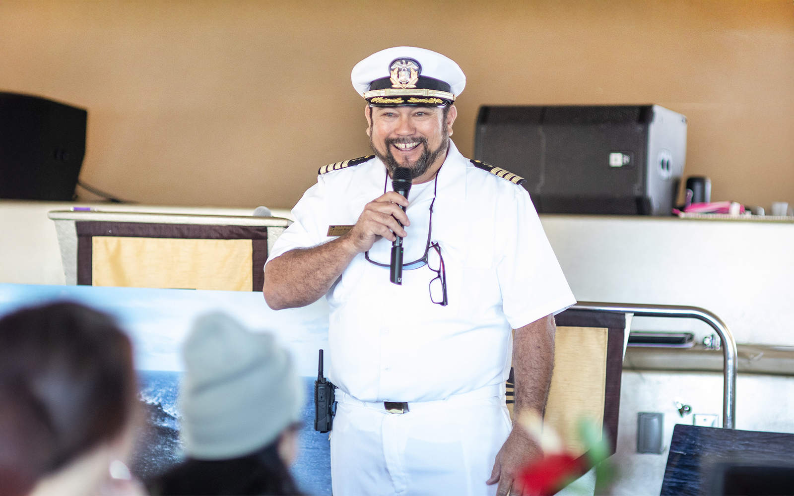 Cruise captain speaking into a microphone on a ship in Oahu.
