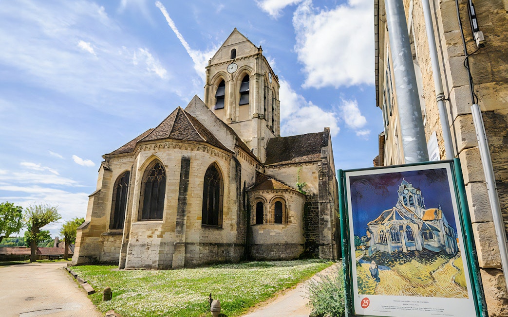 Gothic church in Giverny with a sign displaying Monet's painting, part of a guided tour from Paris.