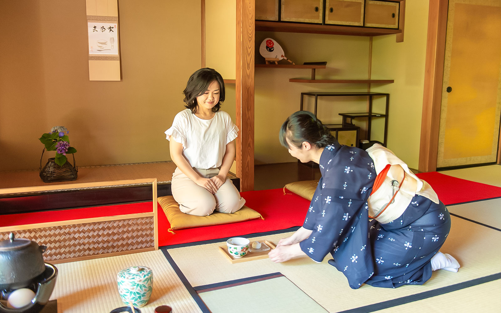 Private tea ceremony in Kyoto teahouse with host in traditional attire serving tea.