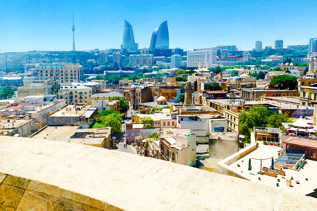 Baku cityscape with Flame Towers and historic buildings, viewed from above.