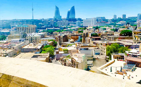 Baku cityscape with Flame Towers and historic buildings, viewed from above.