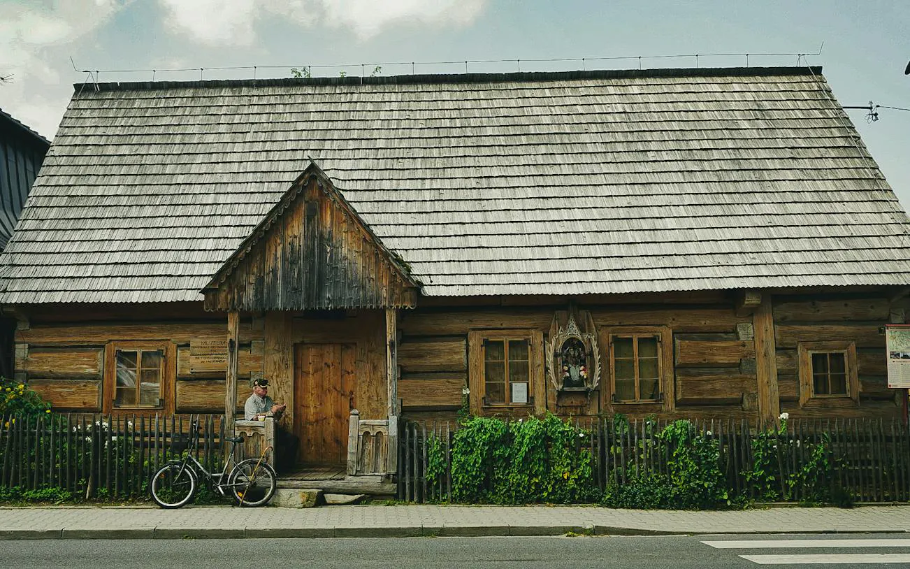 Traditional wooden house in Zakopane with a bicycle and a person sitting on the porch.