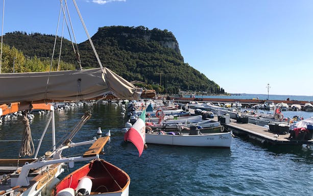 Boats docked at Lake Garda with a view of the surrounding hills, Italy.