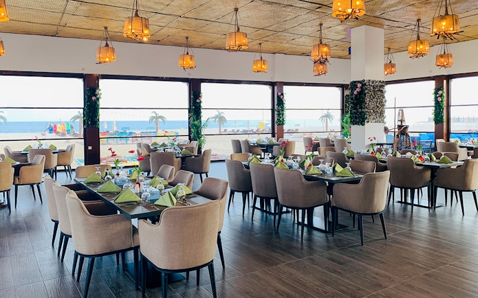 Dining area with ocean view at Al Majles Resort, featuring set tables and hanging lights.