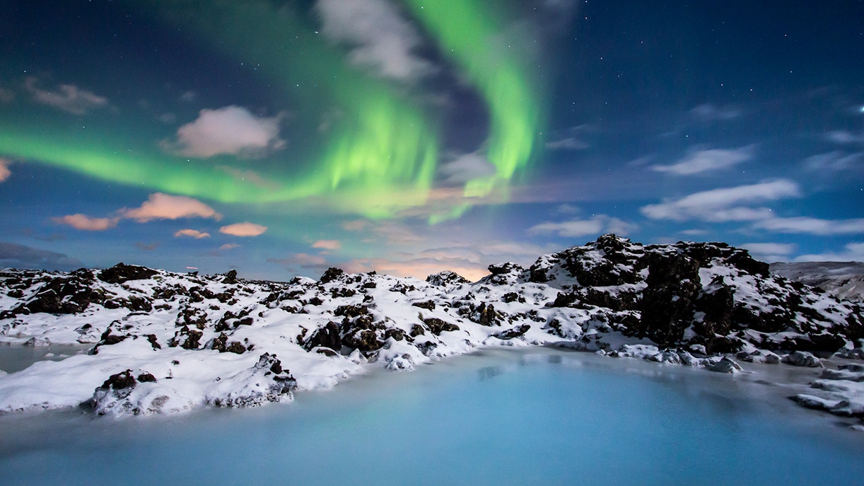 Blue Lagoon geothermal spa with steam rising, surrounded by snow-covered lava fields in Iceland.