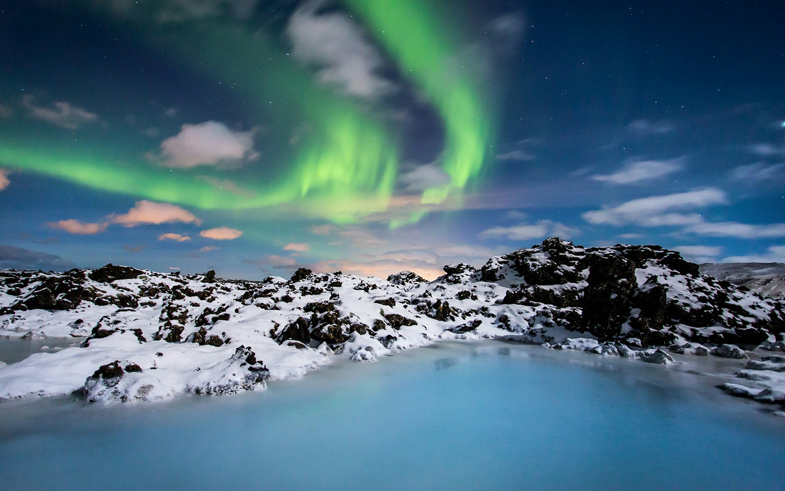 Blue Lagoon geothermal spa with steam rising, surrounded by snow-covered lava fields in Iceland.