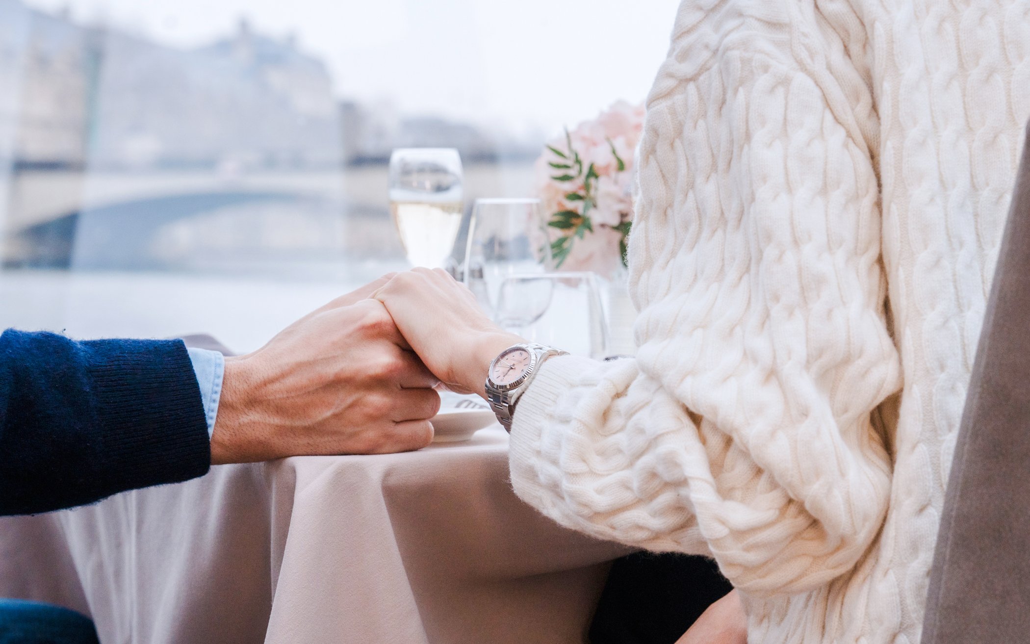 Couple holding hands on a Bateaux Mouches Seine River cruise in Paris.