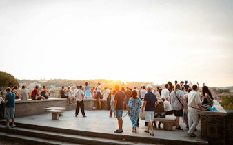 Tourists enjoying a sunset view over Rome from a panoramic viewpoint.