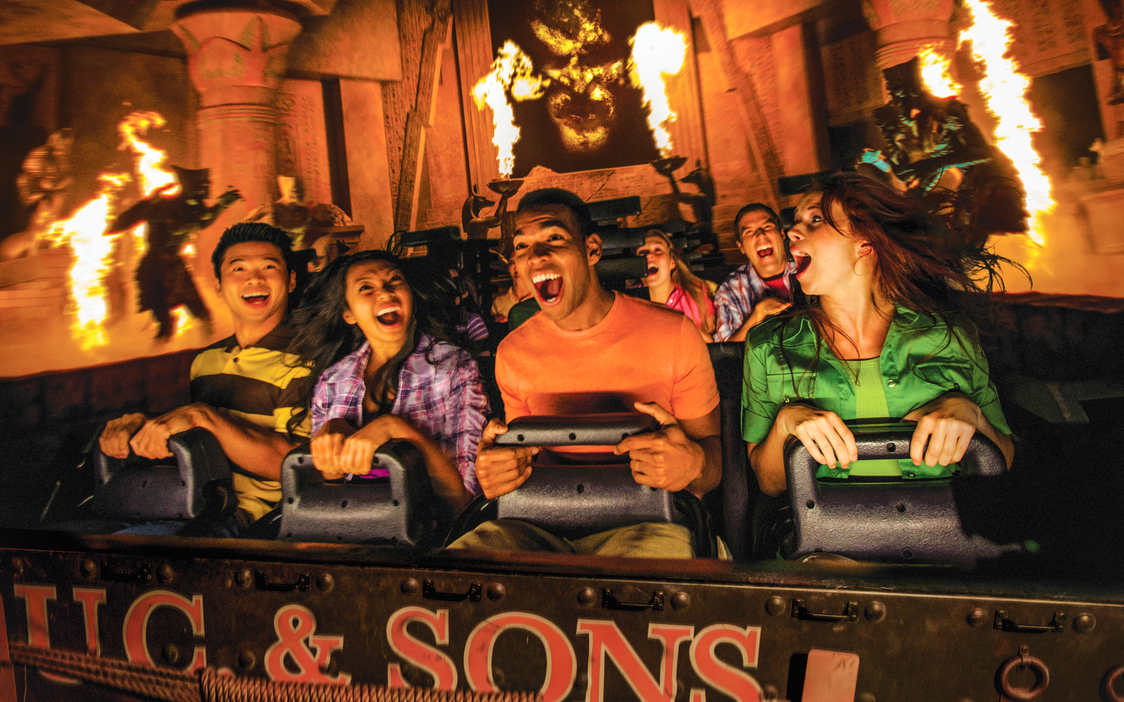 Visitors on Revenge of the Mummy ride at Universal Studios Hollywood, surrounded by flames and ancient decor.