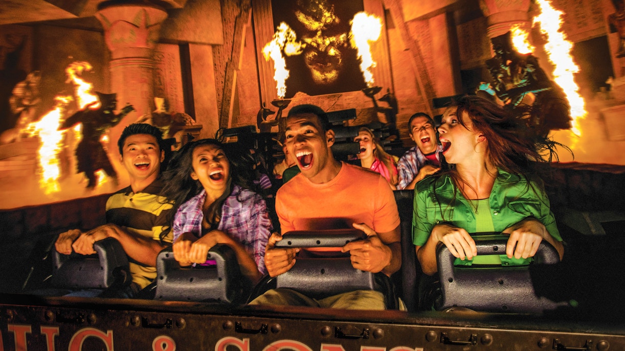 Visitors on Revenge of the Mummy ride at Universal Studios Hollywood, surrounded by flames and ancient decor.