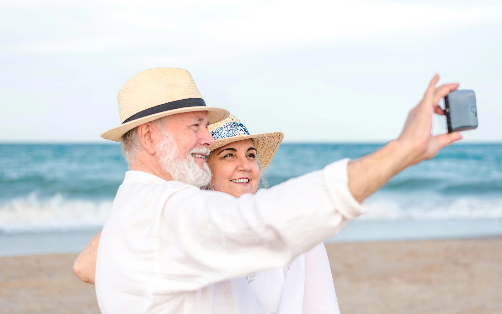 Senior couple taking a selfie on a beach.