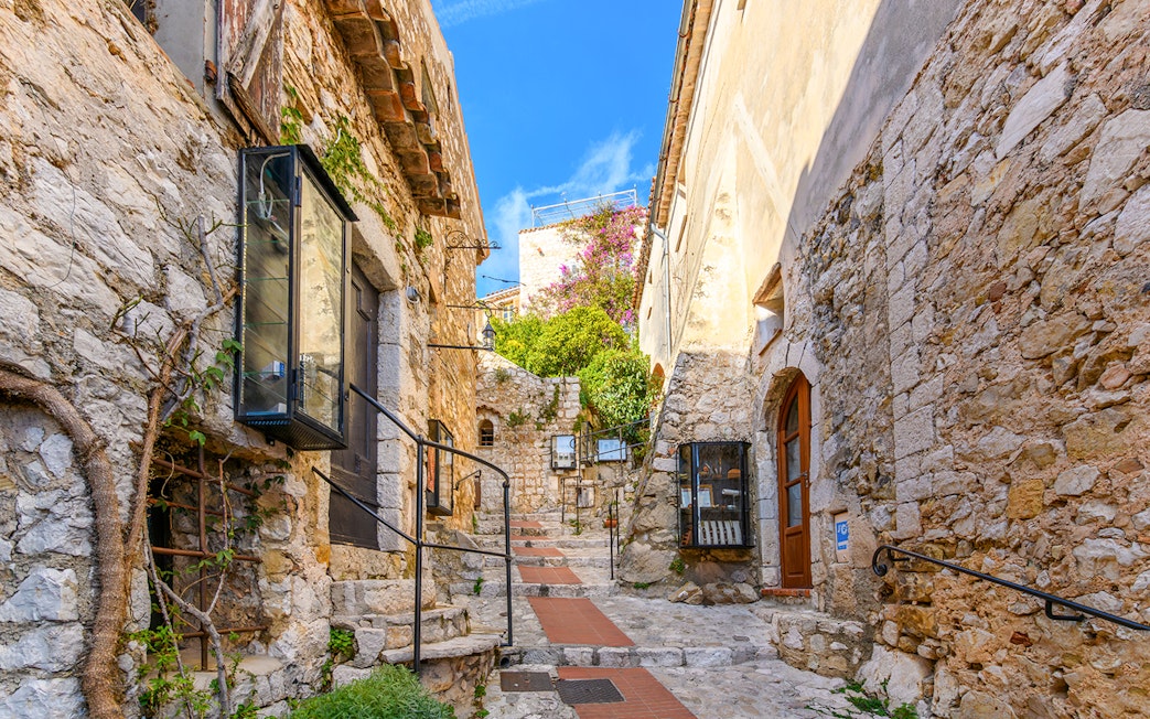 Cobblestone street in Eze, France, with tourists exploring medieval village.