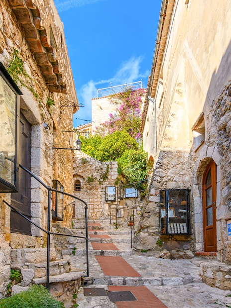 Cobblestone street in Eze, France, with tourists exploring medieval village.