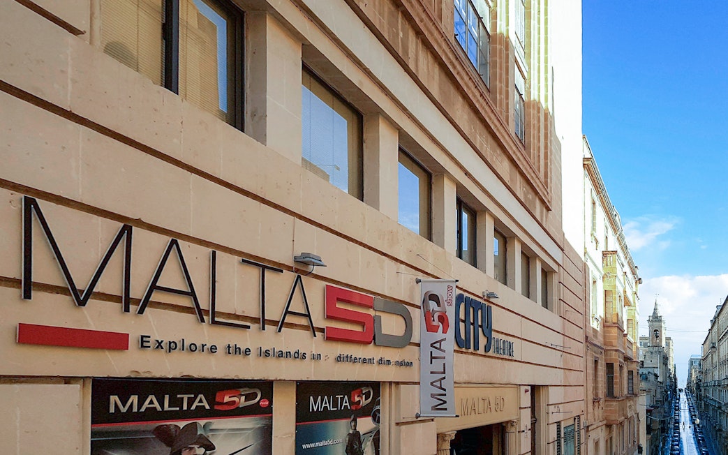 Malta 5D Show entrance on a city street with historic architecture.