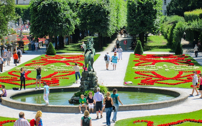 Visitors walking through Mirabell Gardens with vibrant flower beds in Salzburg, Austria.