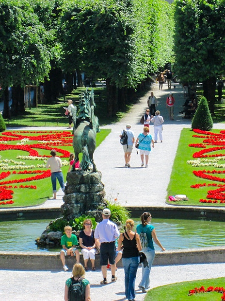 Visitors walking through Mirabell Gardens with vibrant flower beds in Salzburg, Austria.