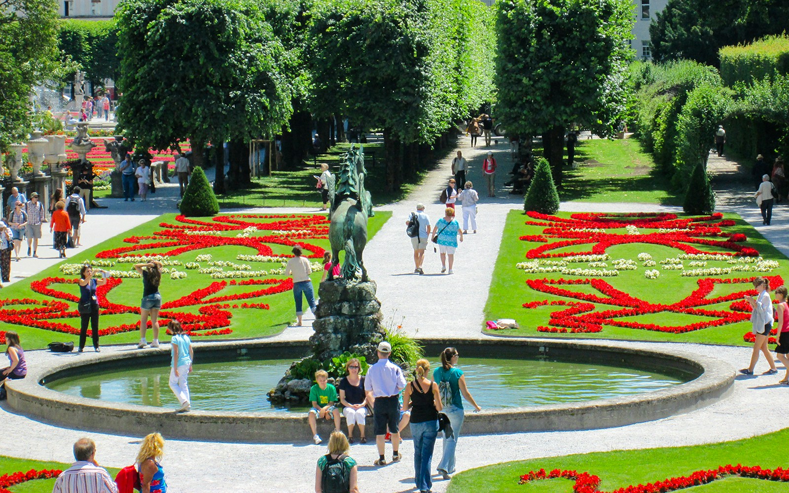 Visitors walking through Mirabell Gardens with vibrant flower beds in Salzburg, Austria.