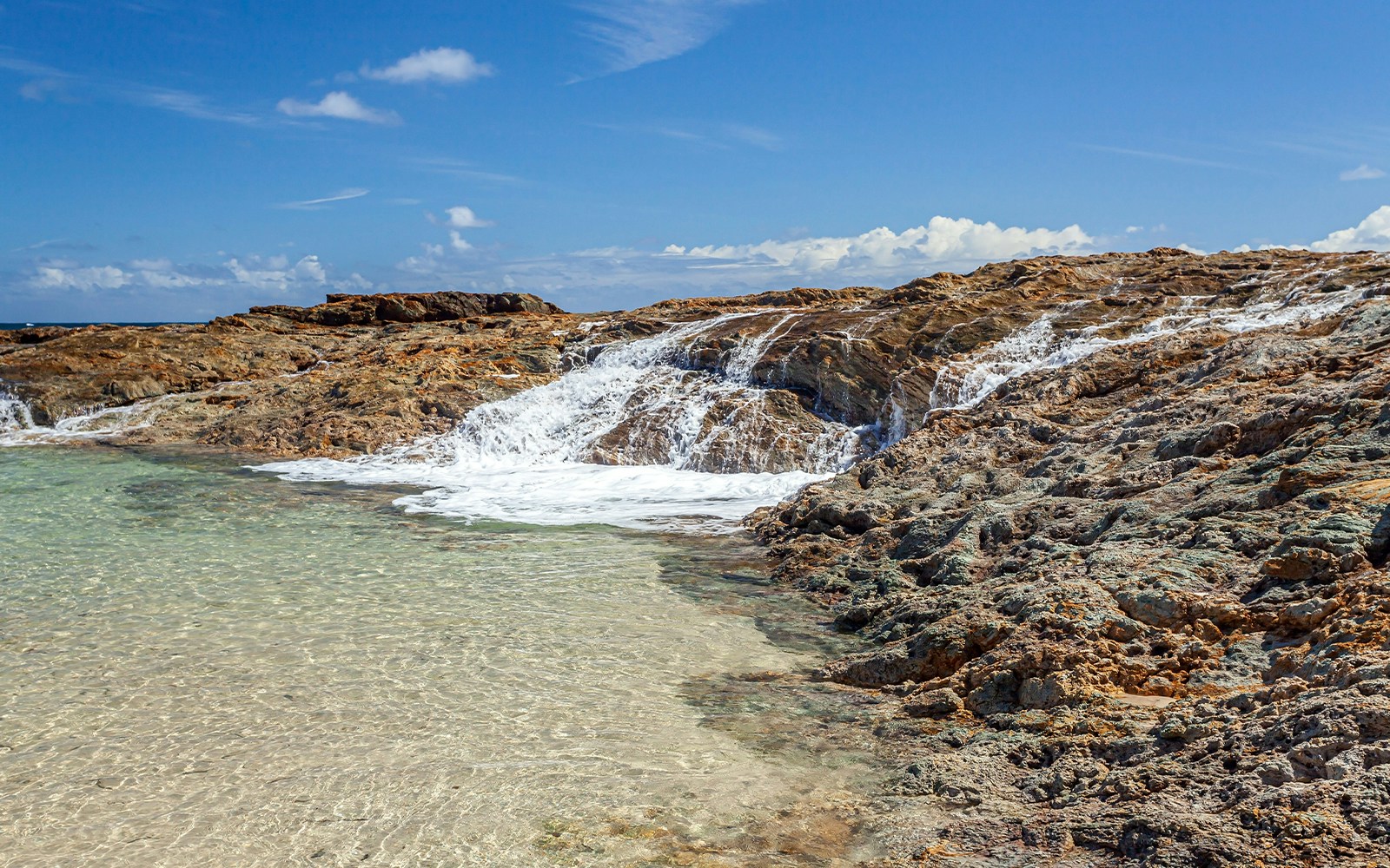 Champagne Pools on Moreton Island with clear water and rocky shoreline.