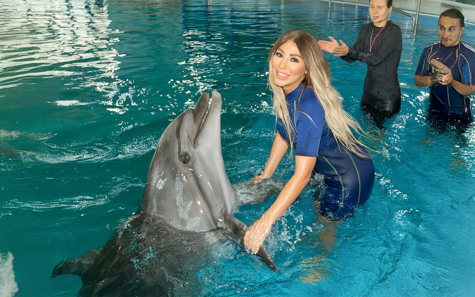 A girl interacting with a dolphin and posing for a picture