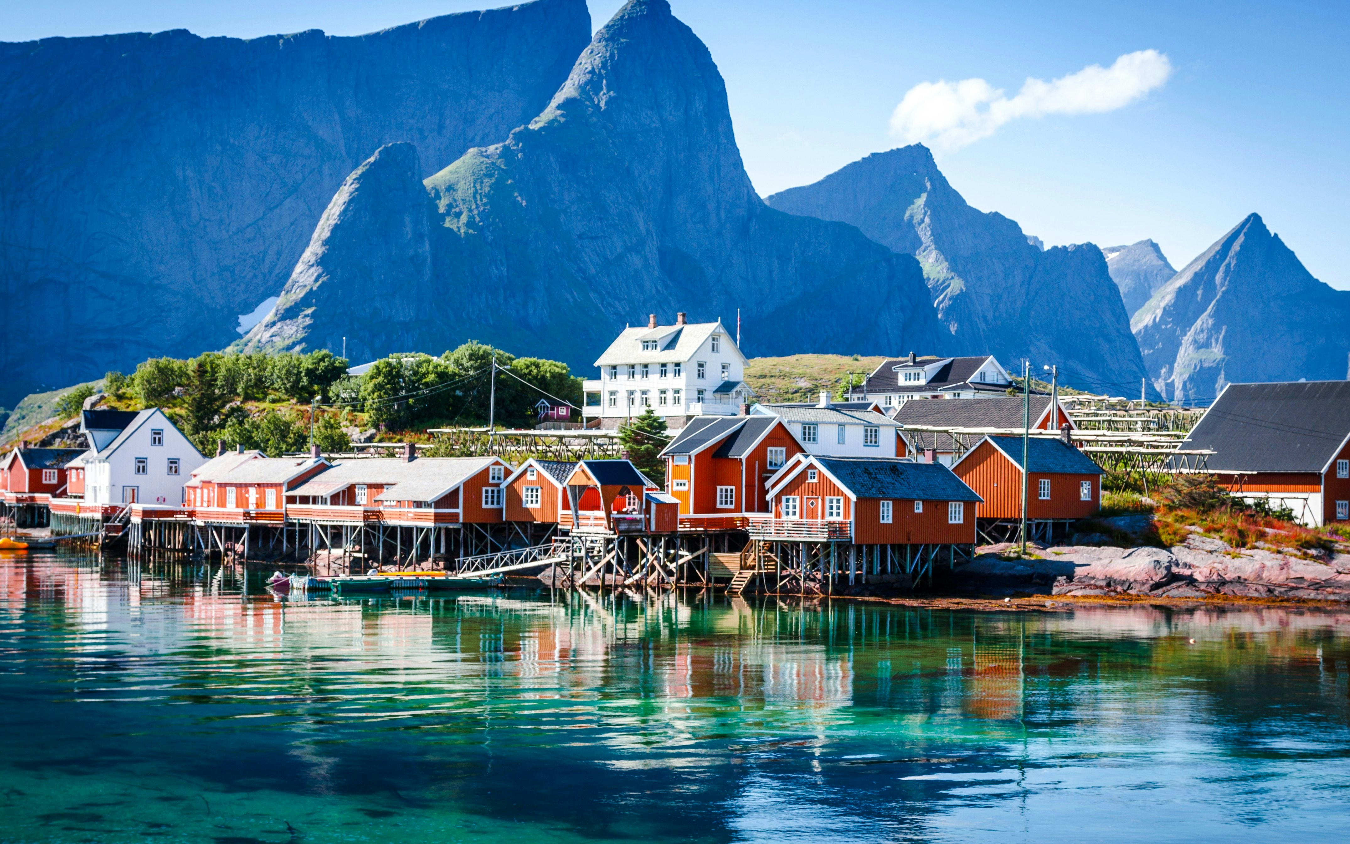 Fishing village with red cabins on stilts, Lofoten, Norway, with mountains in the background.