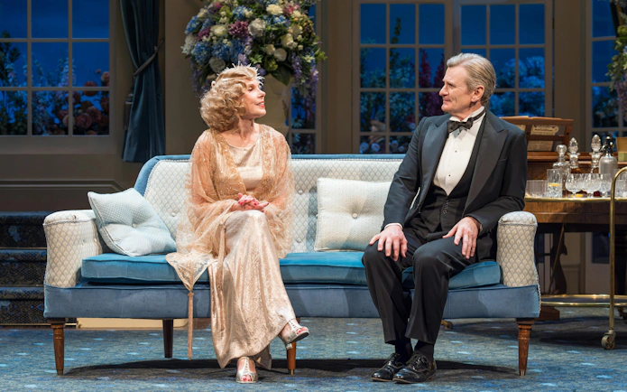 Actors in formal attire on stage during a scene from "HAY FEVER" in Westend.
