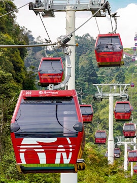 Red cable cars of Awana Skyway ascending through lush forest in Genting Highlands, Malaysia.