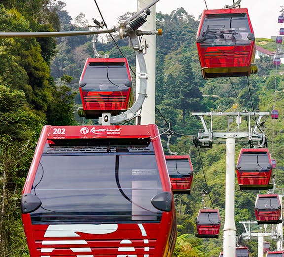 Red cable cars of Awana Skyway ascending through lush forest in Genting Highlands, Malaysia.