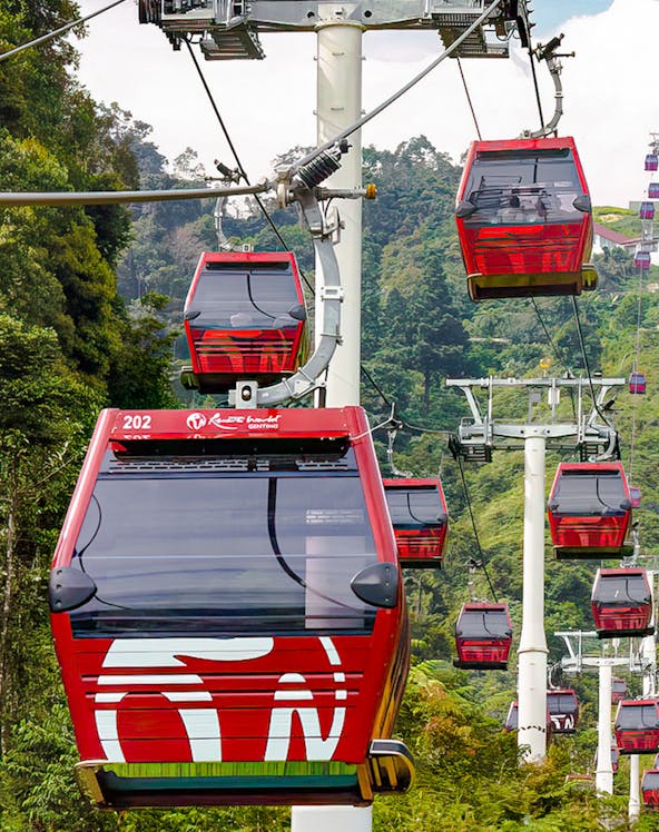 Red cable cars of Awana Skyway ascending through lush forest in Genting Highlands, Malaysia.