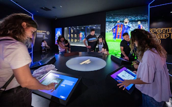Visitors interact with digital displays at Camp Nou Barca Museum's immersive tour.