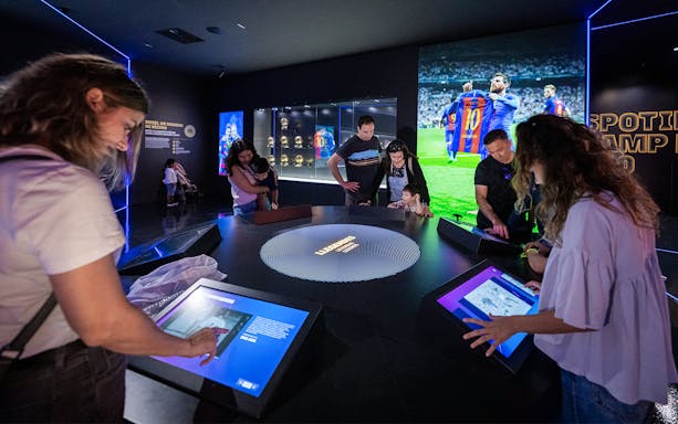 Visitors interact with digital displays at Camp Nou Barca Museum's immersive tour.
