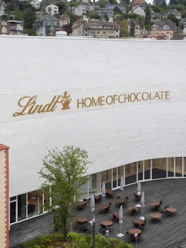 Lindt Home of Chocolate Museum exterior with outdoor seating area in Switzerland.
