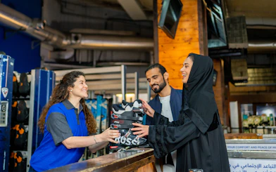 Ski Dubai visitors receiving ski boots from staff at Snow Park entrance.