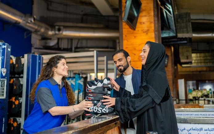 Ski Dubai visitors receiving ski boots from staff at Snow Park entrance.